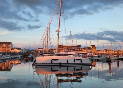 Fountaine Pajot Tanna 47 en vente chez Neo Marine, vu de loin, au lever du jour, amarré dans un port breton.